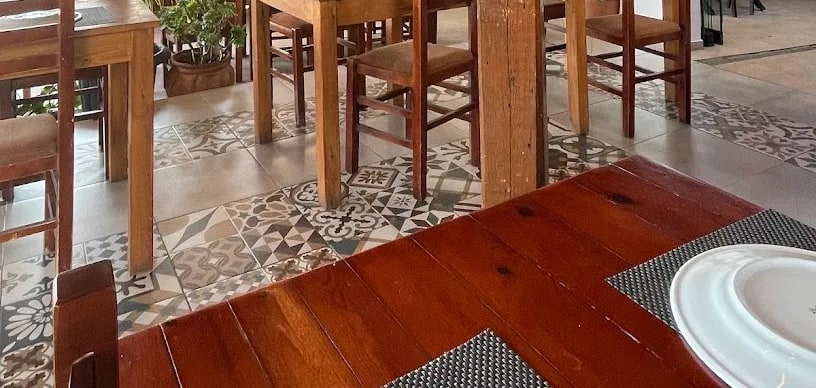 Wooden tables and chairs on a patterned encaustic tile floor in the dining room at Taverna Velco