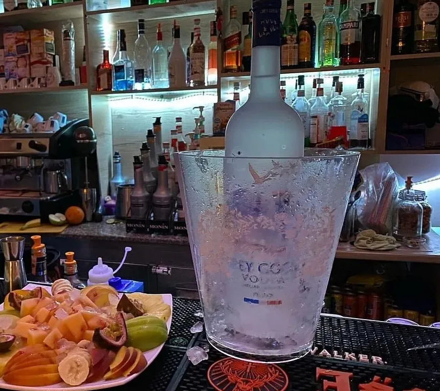 The back bar at Lido Lounge: a lit spirits wall, a rack of syrups, an espresso machine and a plate of cut fruit