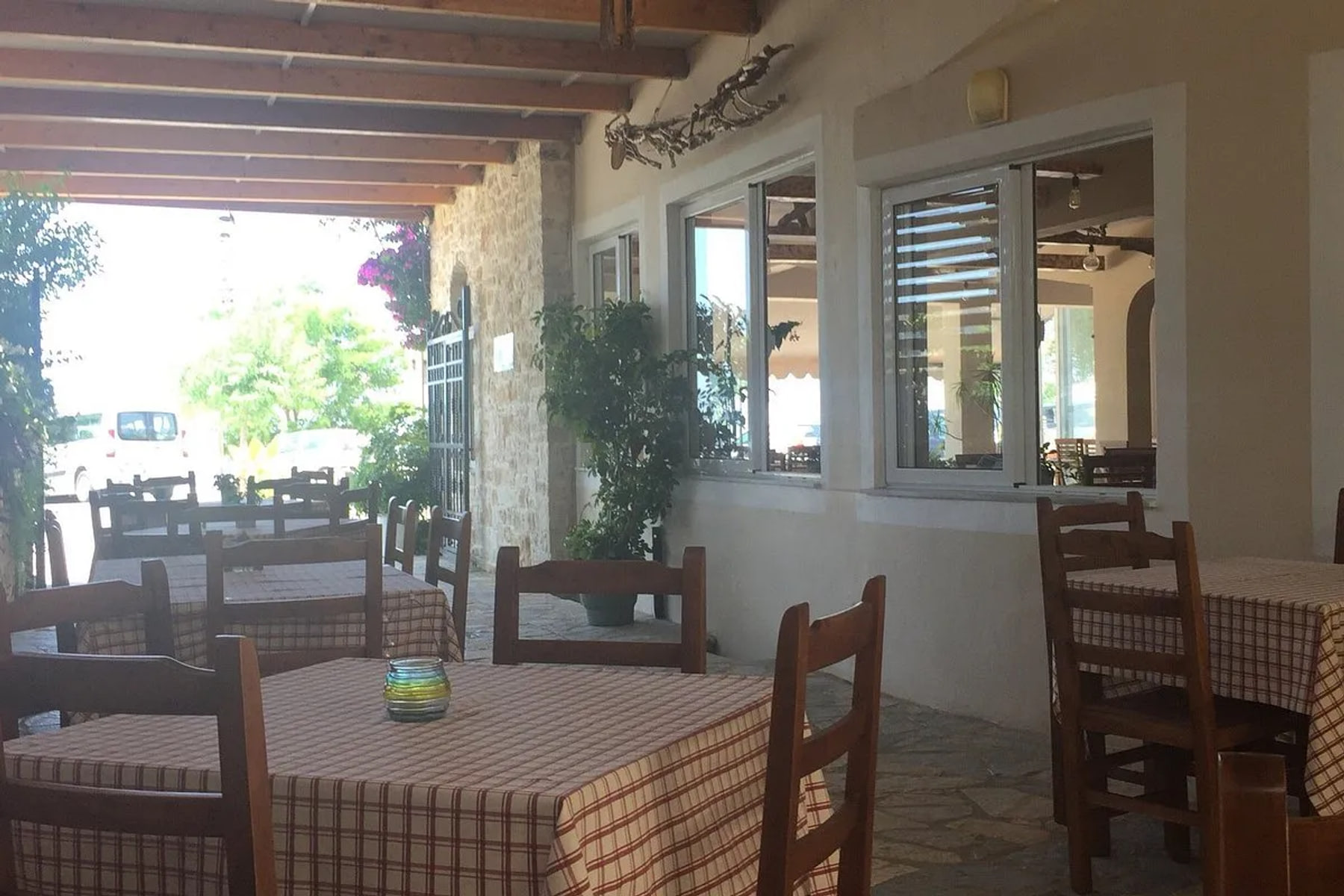 Checked cloths and wooden chairs on the covered terrace at Restaurant Kolagji in daylight