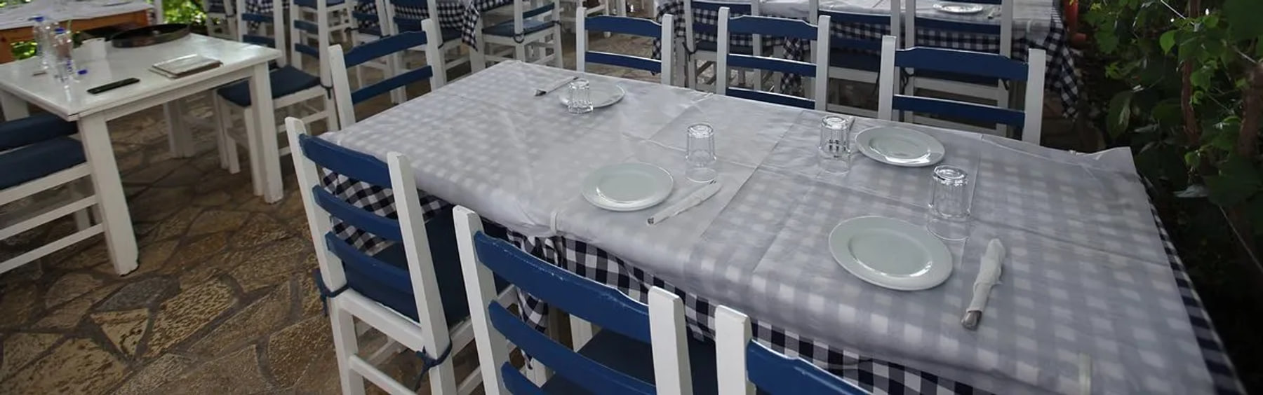 Laid tables under the white slatted pergola ceiling, with the green canopy along one side
