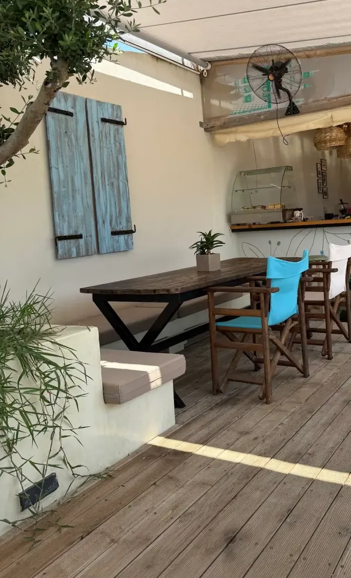 The covered deck at Tonea's Brunch Bar — a long dark table, director's chairs and an olive tree against a whitewashed wall