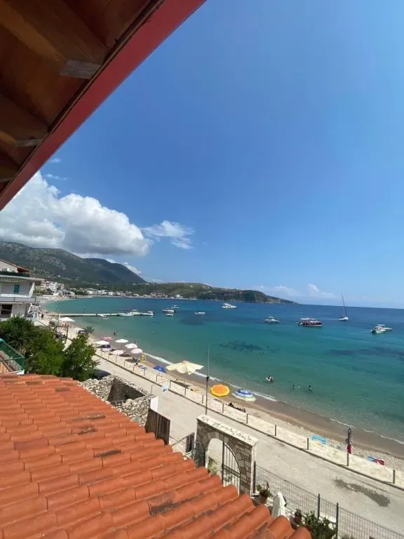 The bay at Himarë seen from an upper balcony of AngelView Apartments, over the terracotta roof to the beach, the moored boats and the headland