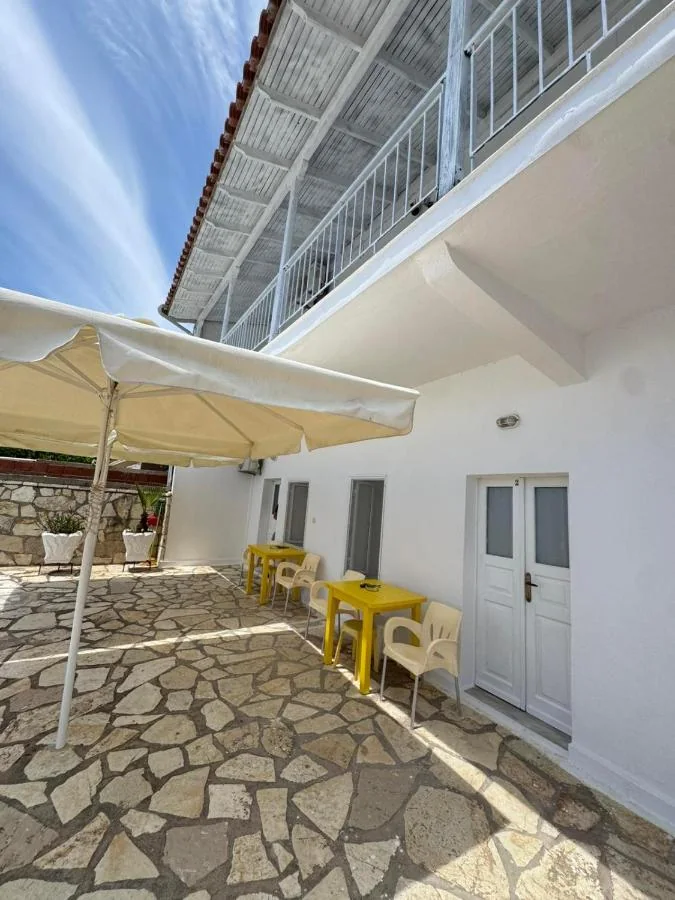The shaded inner courtyard at AngelView Apartments, with a parasol, tables and the white doors of the ground-floor apartments