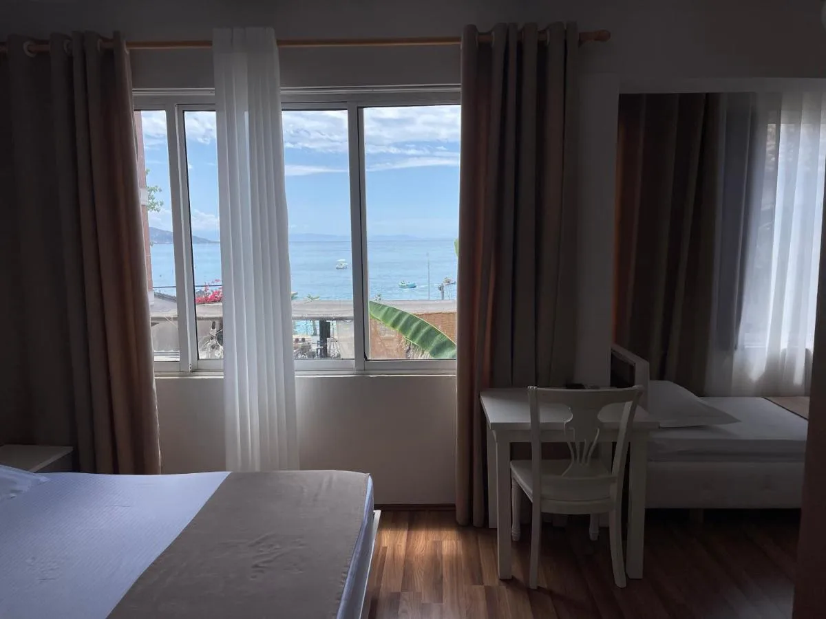 A guest room with a wide window over the bay, a writing desk and chair, wooden floor and a second bed beyond.