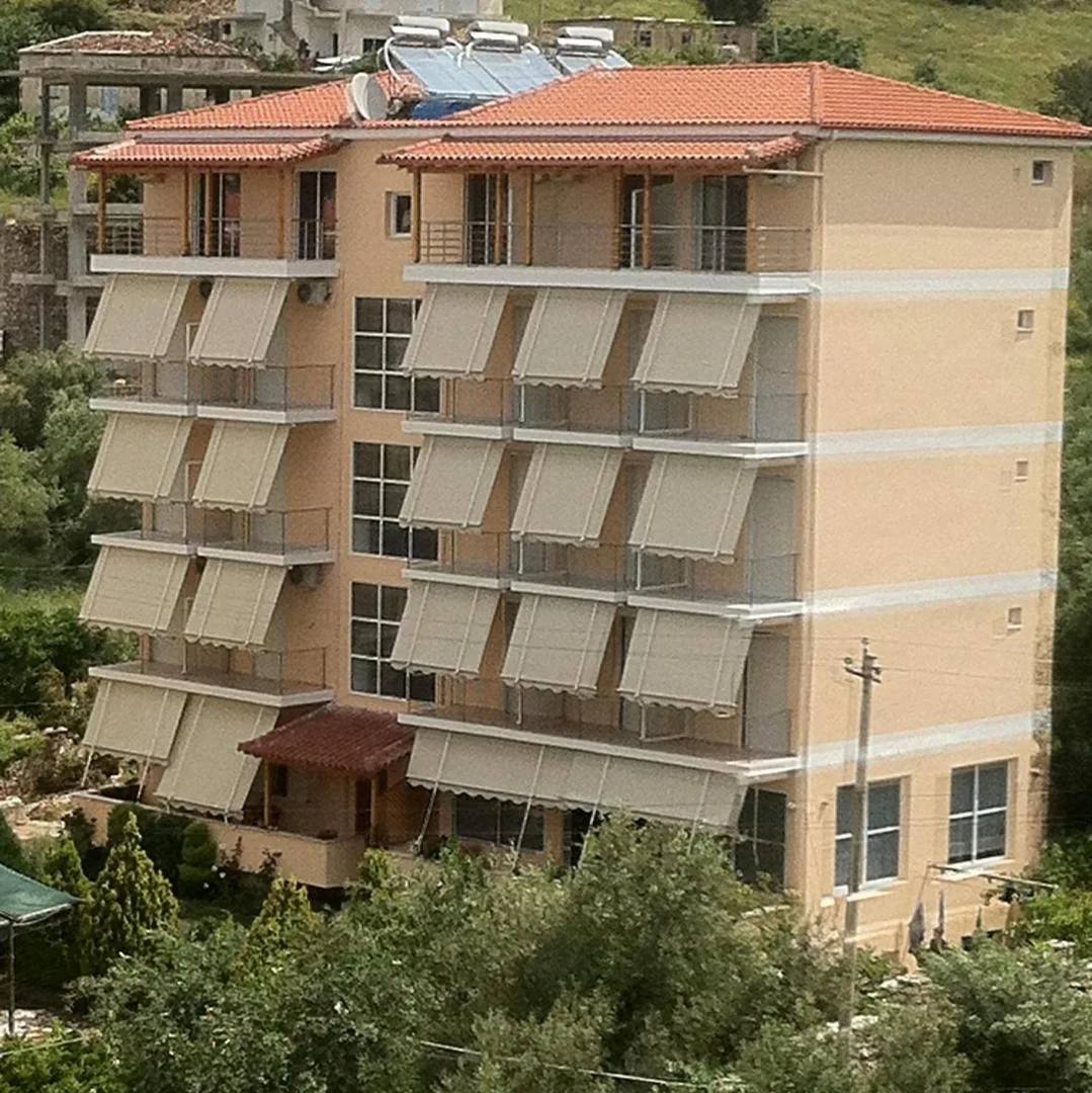 The five-storey ochre building of Areti Rooms Hotel with cream drop-awnings and a pantile roof