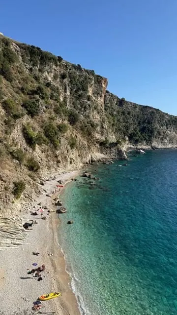 The cove at Gjiri i Filikurit under steep cliffs, with turquoise water