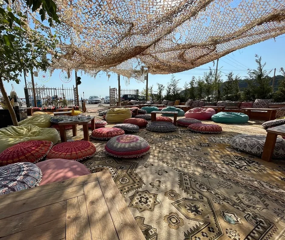 Round mandala floor cushions and bean bags on overlapping kilim rugs under the netting at Boho Livadh