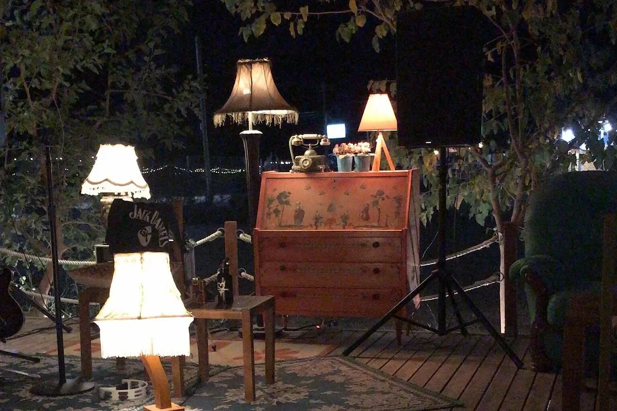 Fringed standard lampshades, a painted bureau and a rotary telephone on the deck at Boho Livadh after dark