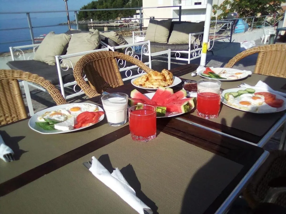 A second view of the terrace breakfast table, wicker chairs and cushioned benches facing the water.