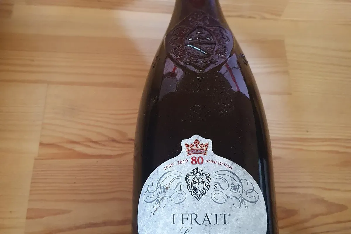 A bottle of I Frati Lugana, Cà dei Frati, on a pine table