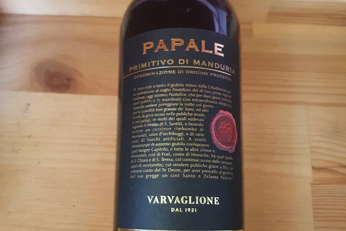 A bottle of Papale Primitivo di Manduria, Varvaglione, on a pine table