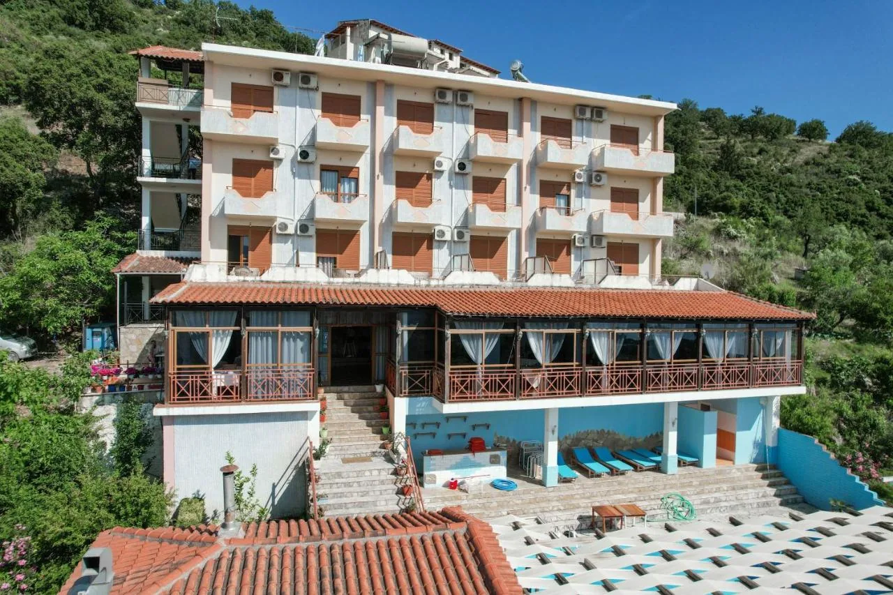 The front of Hotel Panorama: three floors of balconies with terracotta roller shutters above a glazed veranda under a pantile roof, and a lounger terrace below.