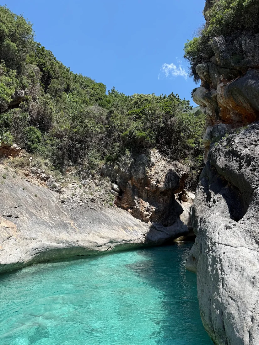 Turquoise water in the narrow limestone inlet of Butterfly Cove on the Albanian Riviera coast