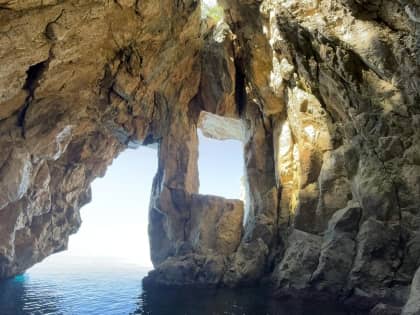 Tour boat anchored in crystal-clear waters along the Albanian Riviera coastline