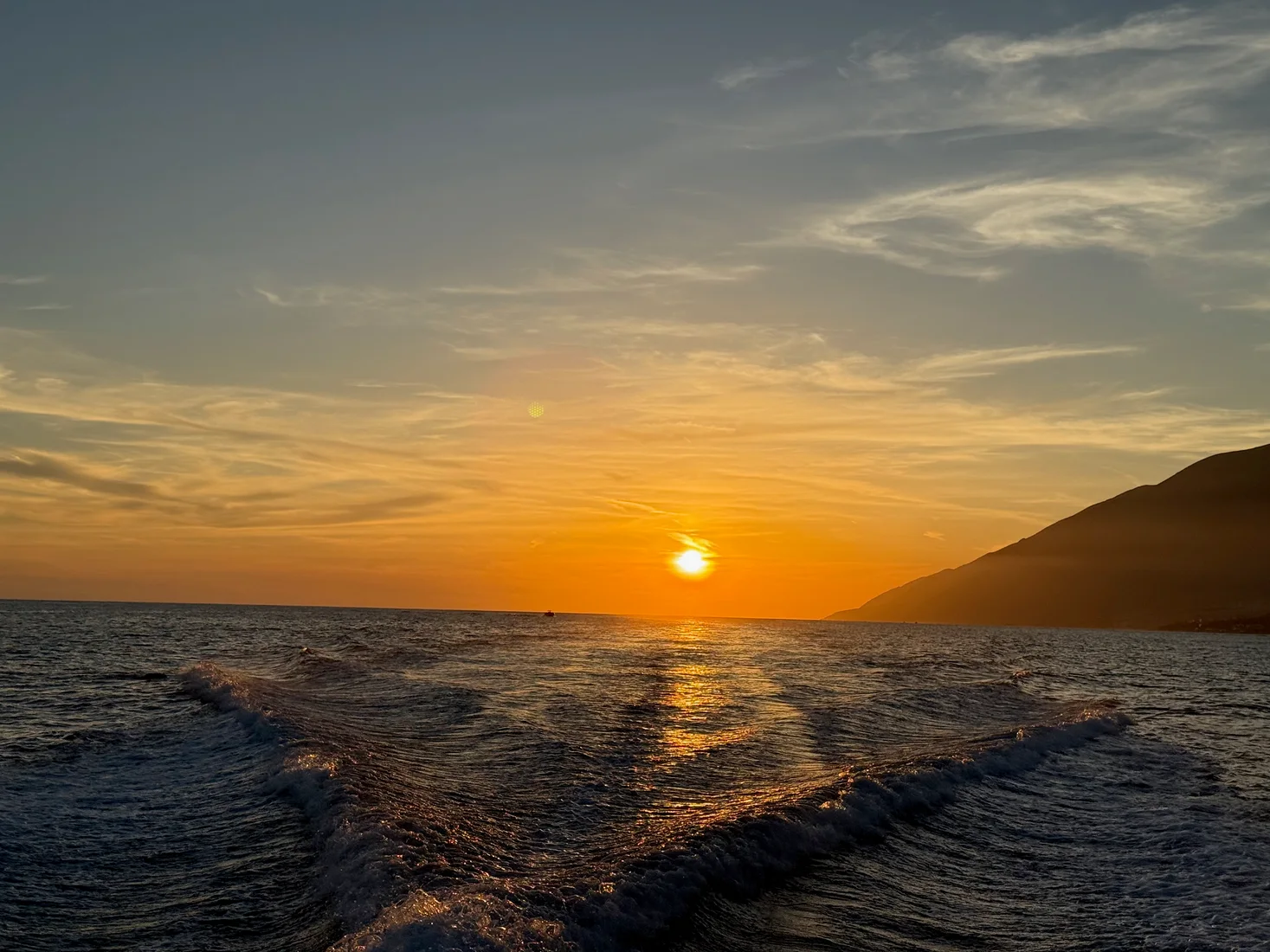Boat on the Ionian Sea at golden hour during a Himara sunset cruise, Albanian Riviera