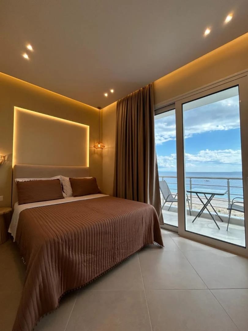 A double room facing the sea, brown ribbed bedspread and a balcony table looking over Livadhi Beach