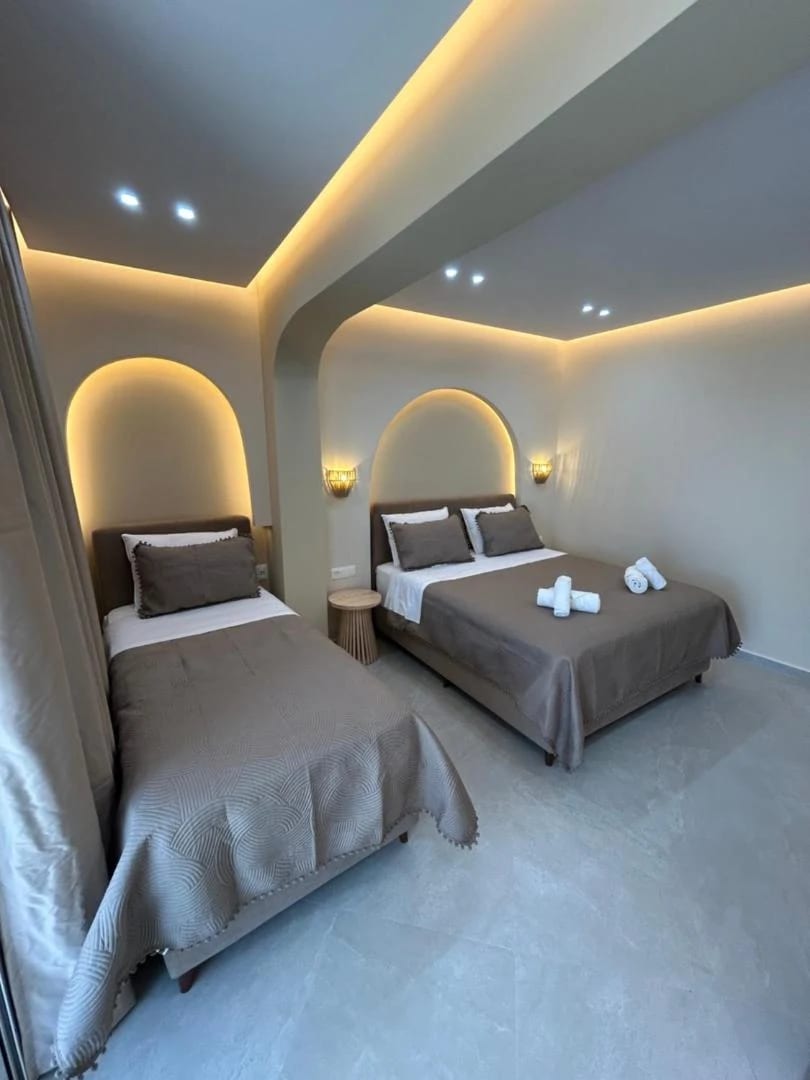 A triple room with two beds, each under its own arc of concealed light
