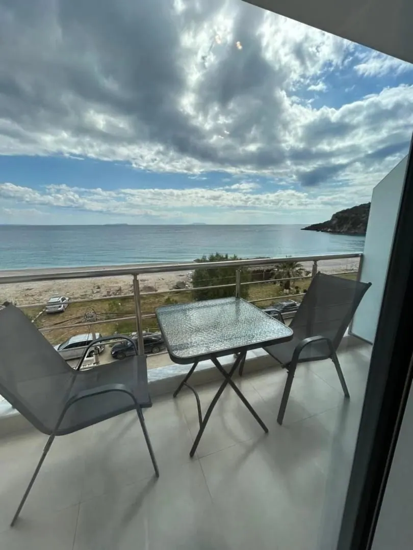 A balcony table and chairs above Livadhi Beach, the bay curving away towards the headland