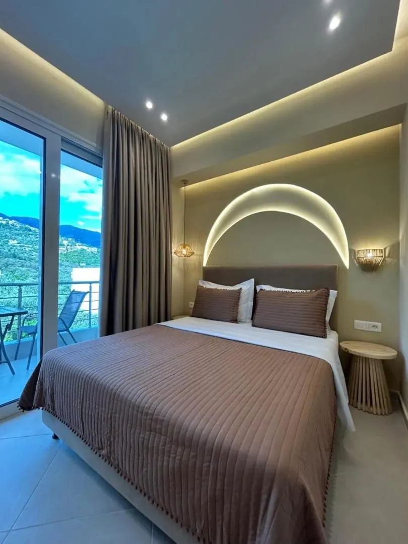A room with an arc of concealed light above the bed and a balcony opening onto a green hillside