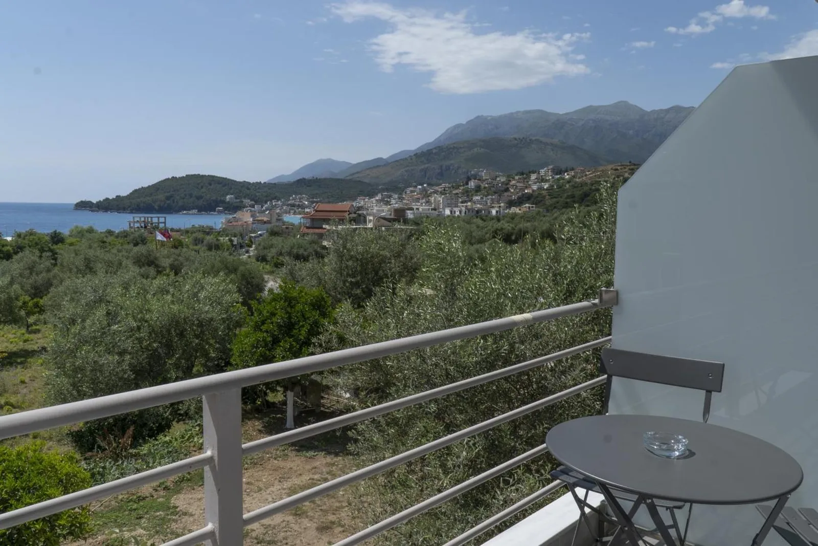 A balcony table and chair looking over the olive grove to Himarë and the sea