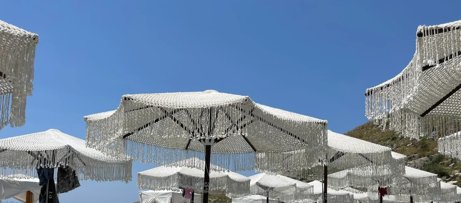 Knotted bobble fringe hanging from the club's canopies against a clear midday sky