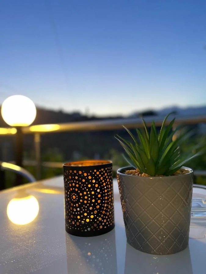 A pierced metal lantern and a potted succulent on a white terrace table against a deep blue evening sky