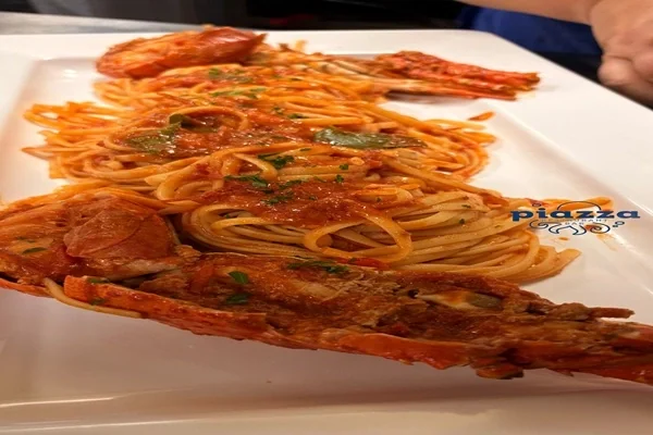 Spaghetti in tomato sauce with shell-on shellfish, served on a long white platter