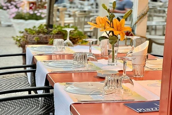 Terrace tables laid with copper-terracotta runners, glassware and orange lilies