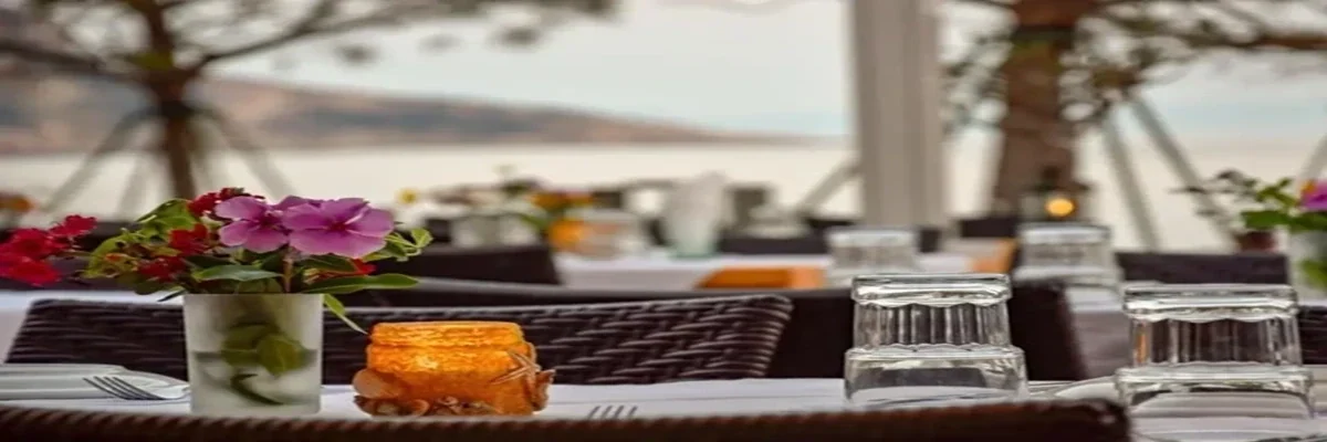 A laid table on the terrace at Piazza, glassware and flowers in close focus with the bay behind