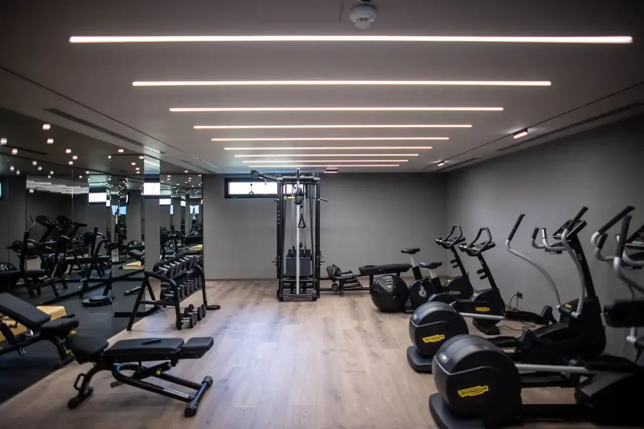The fitness centre at Prado with cardio machines and free weights under linear lighting