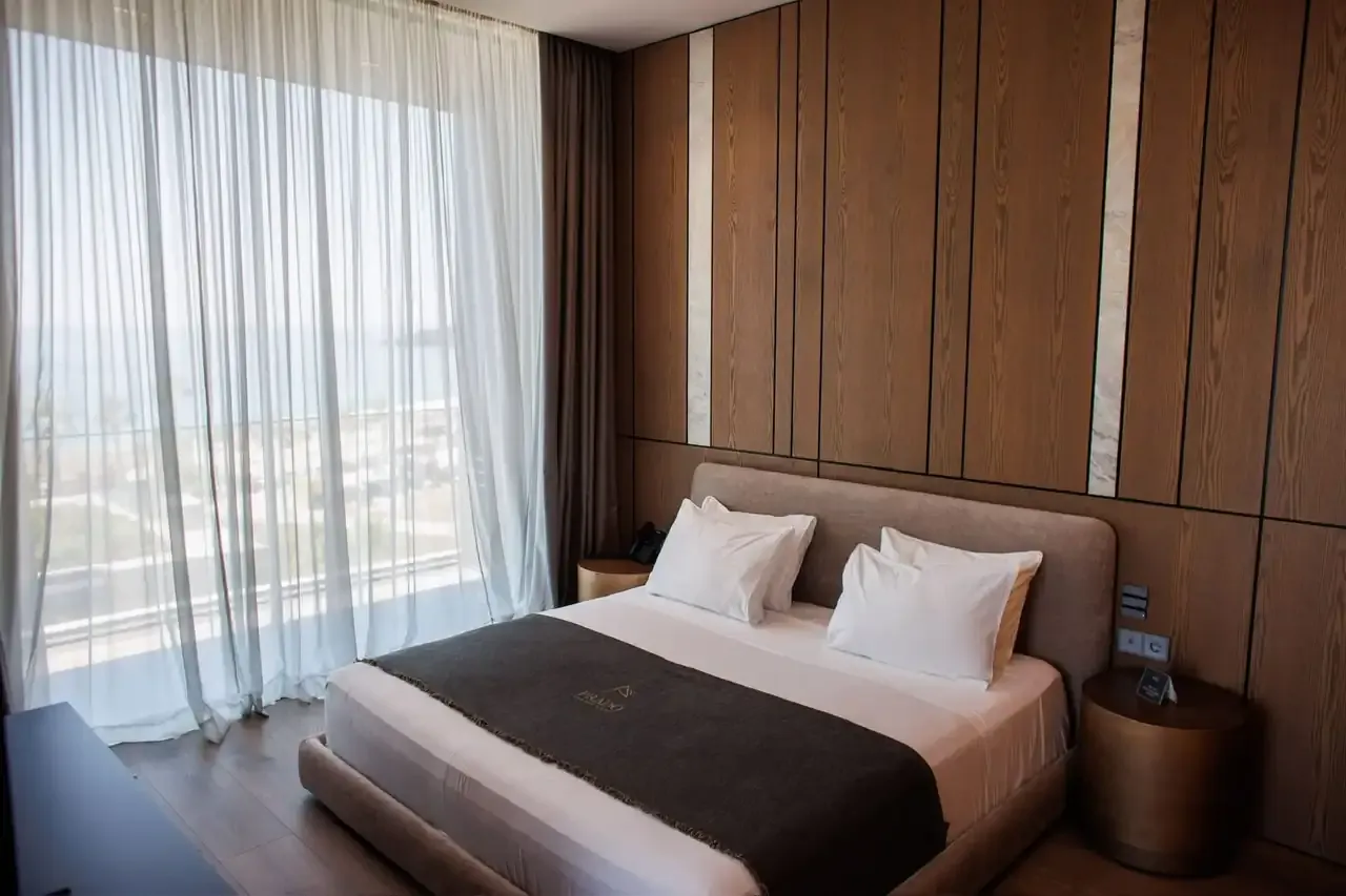 The bedroom of the Deluxe Suite in earth tones with timber panelling