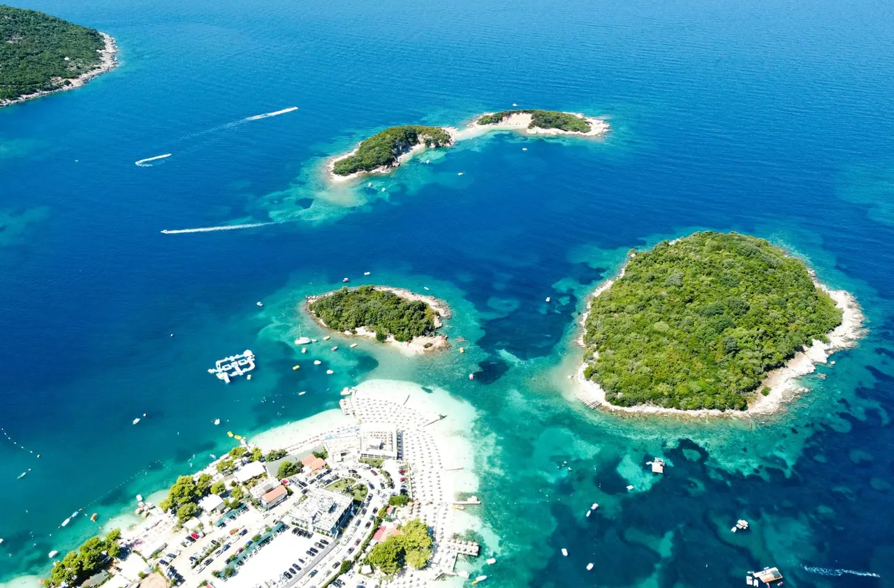 Aerial view of the Ksamil archipelago — four green islets in the turquoise Ionian Sea, southern Albania