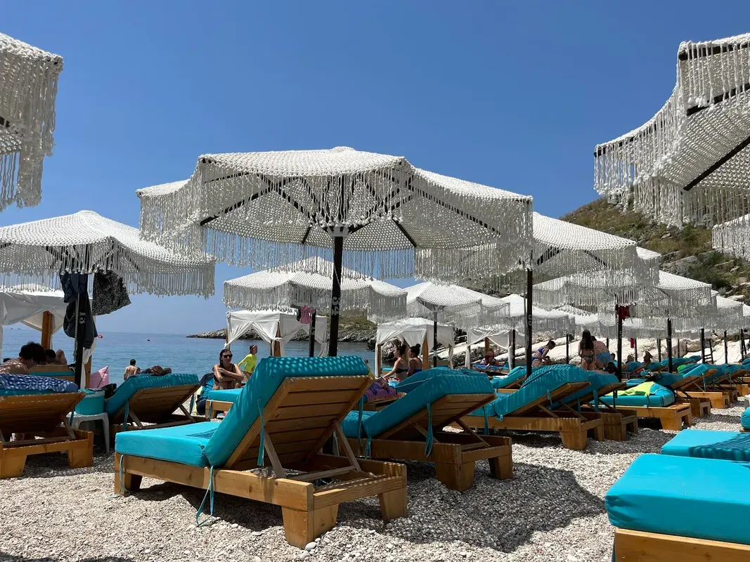 Mumbas Beach Club's fringed white umbrellas and turquoise-cushioned loungers on Llaman Beach