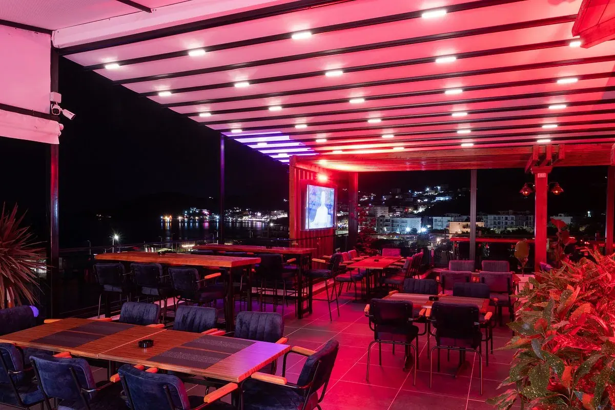 Rooftop Nia Boutique's pergola-covered terrace seating overlooking Himara bay at sunset