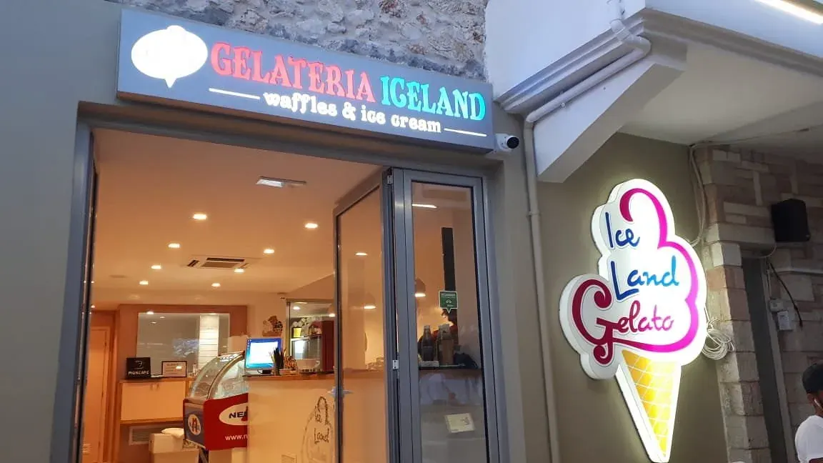 Soft-serve cone and a cup of pistachio gelato held in hand at Iceland Gelato in Himara