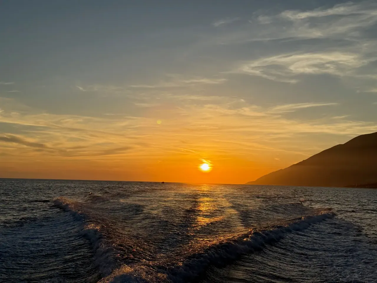 Boat on the Ionian Sea at golden hour during a Himara sunset cruise, Albanian Riviera