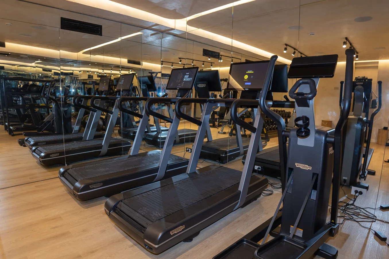 Treadmills and cross trainers along the mirrored wall of the gym