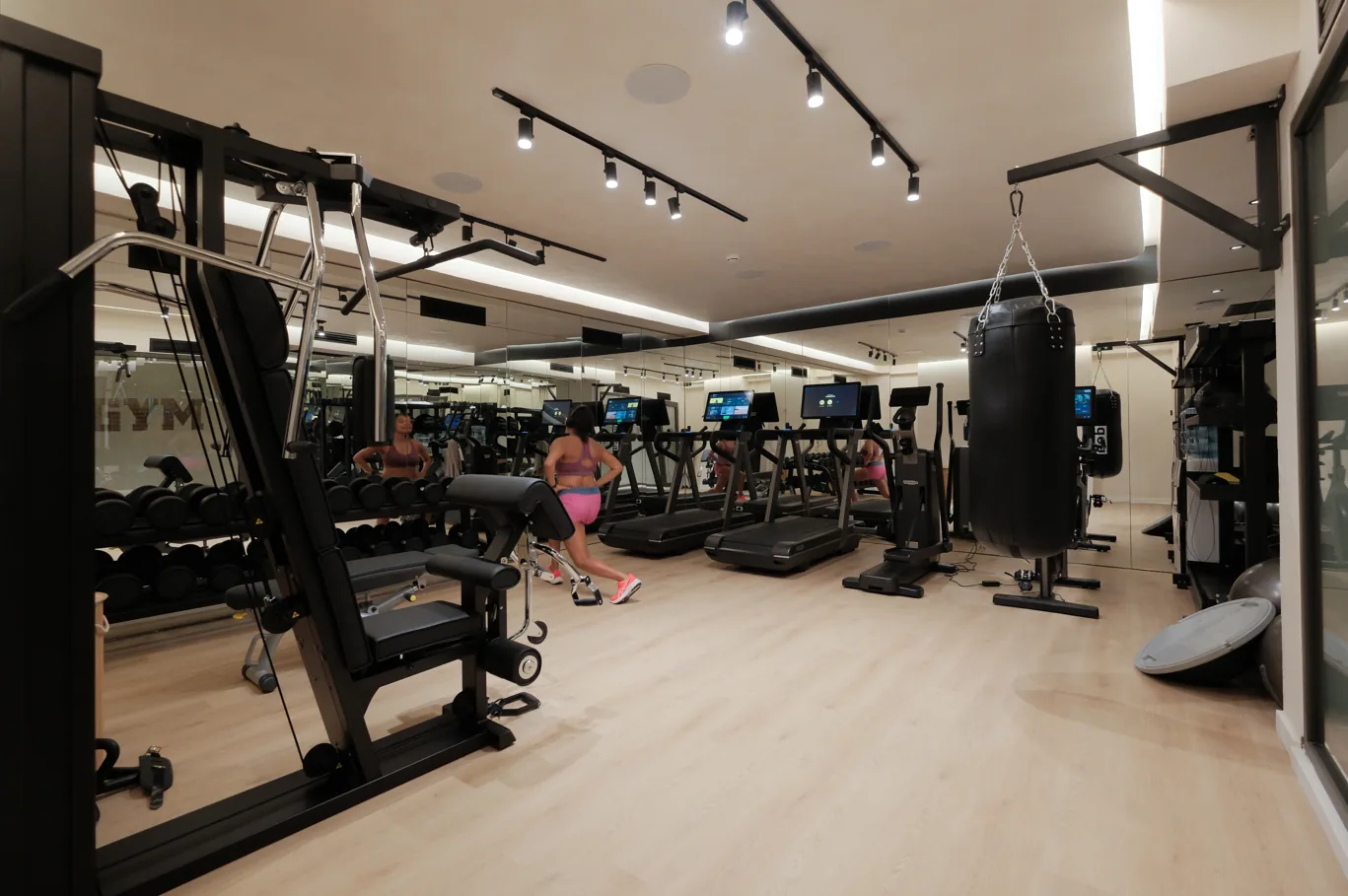 The hotel gym, cardio machines and resistance stations under track lighting