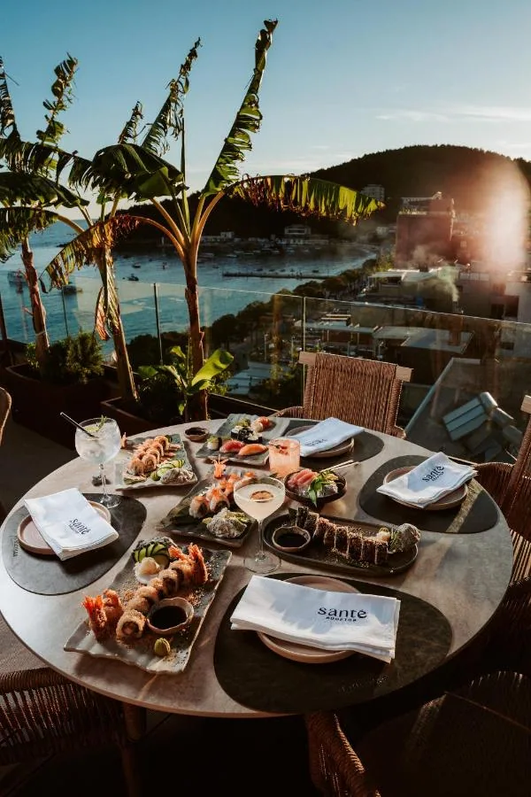 Dishes on a table on the roof at sunset, palms and the bay behind