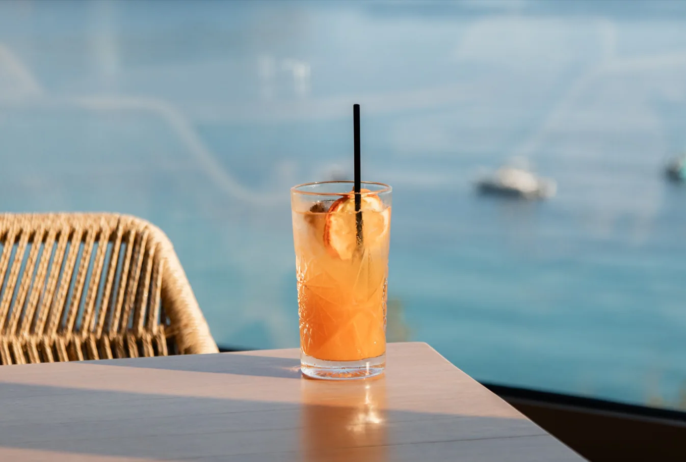 A long drink on a table with the water behind it