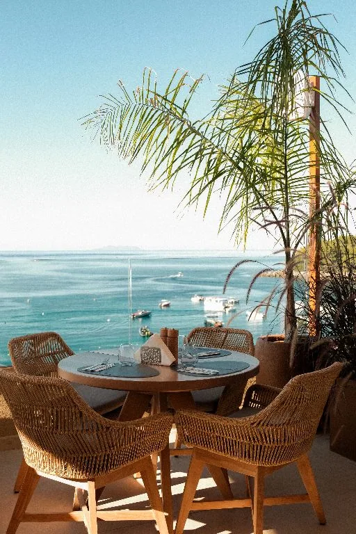 A table for two on the roof with the bay and the palms behind
