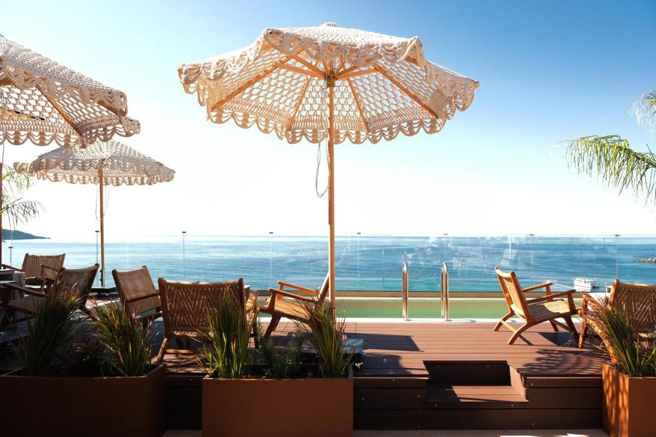 Crocheted parasols and rattan chairs on the roof terrace, the sea beyond the balustrade