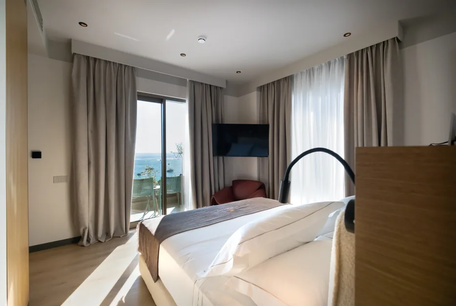 The bed in a Junior Suite with the sea through the window