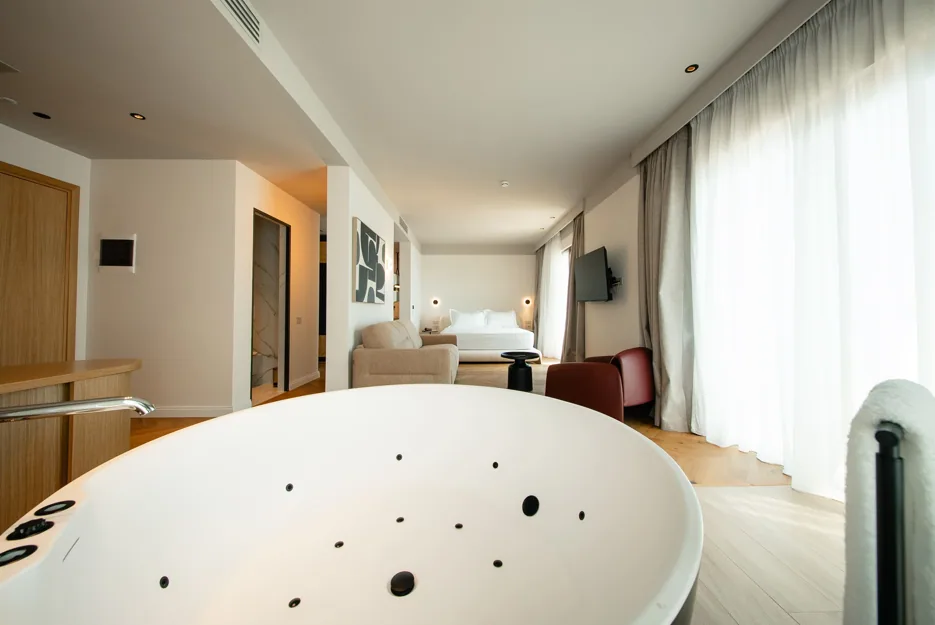 The whirlpool bath standing in Suite 305, bed and windows beyond