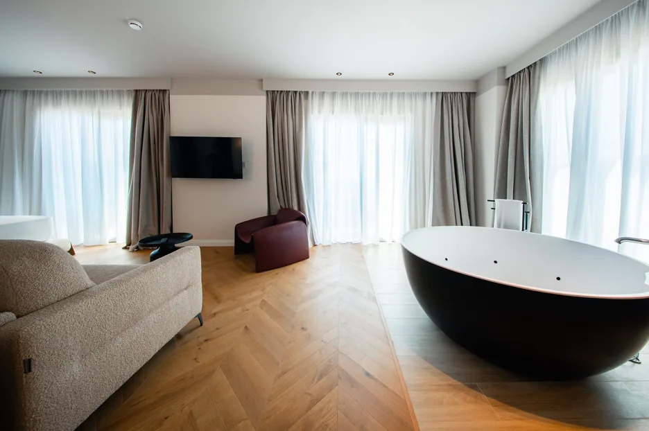 A black egg-shaped freestanding bath on a herringbone oak floor