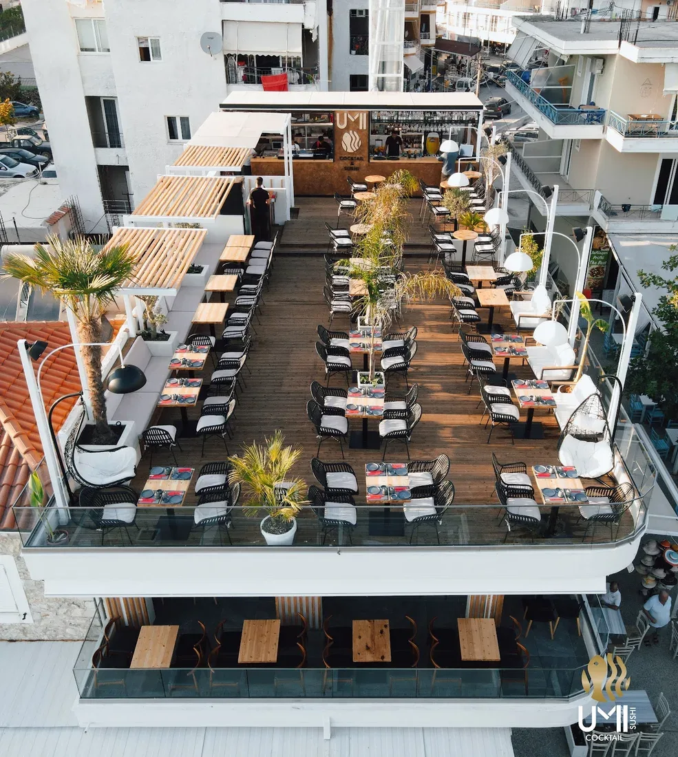 UMI's rooftop deck photographed from above, tables in two long rows along the timber decking, the open bar at the far end under its own wordmark