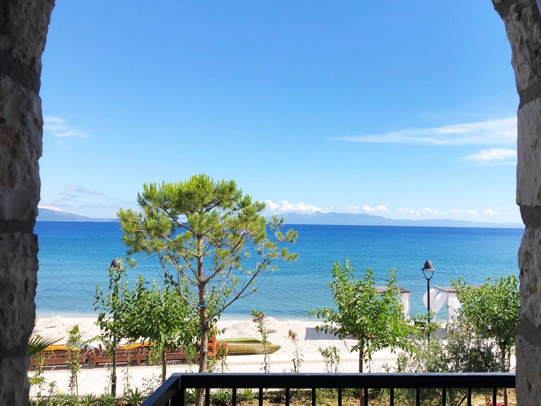 The bay and the beach seen from a room balcony over the tops of the pines