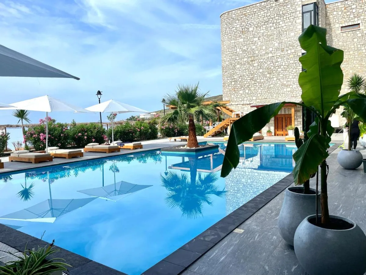 The pool from above, its water wrapping a planted island of palms with white loungers along the edge