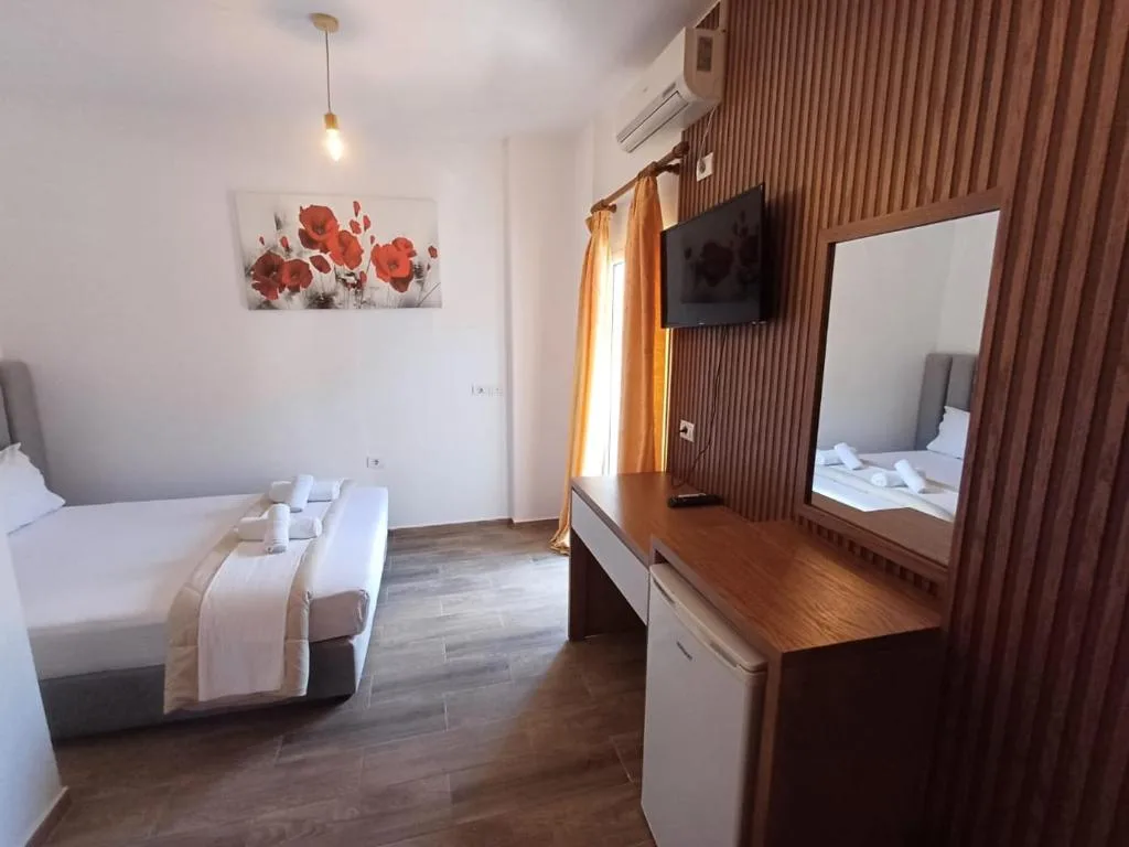 A room at Velco BB Himara with a slatted timber wall, a desk and a wall-mounted television