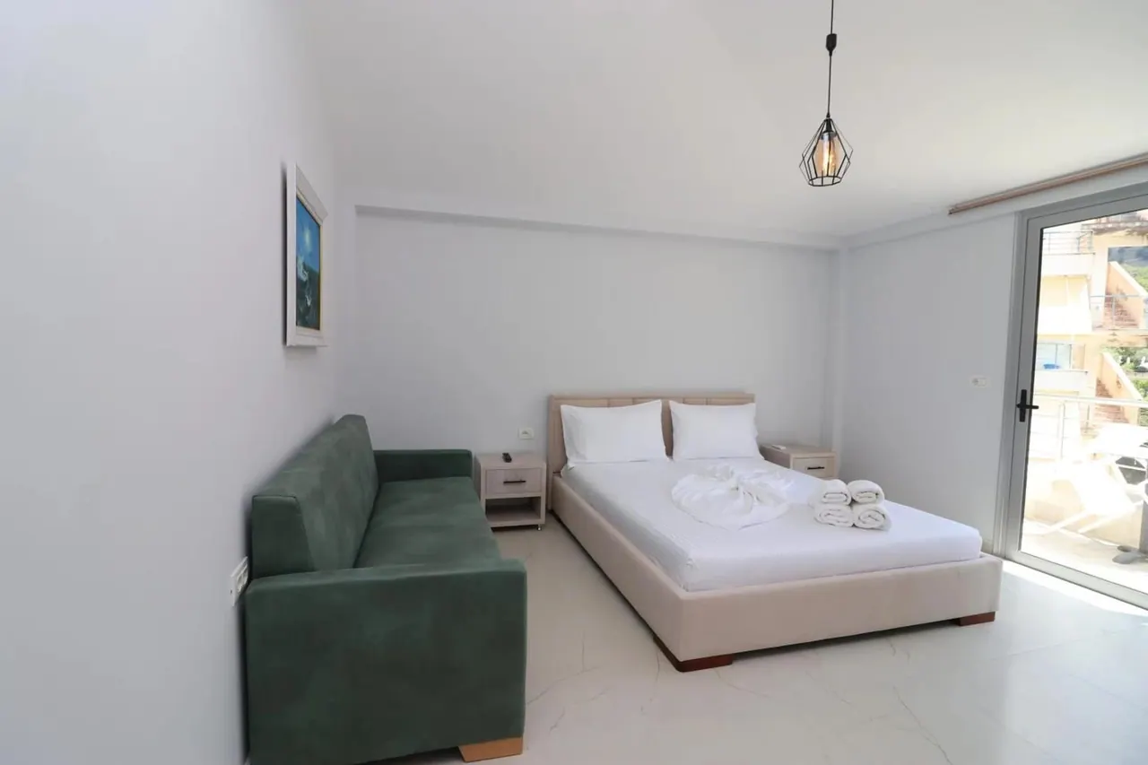 Bedroom with a wide bed, a green sofa and a sliding door onto the balcony